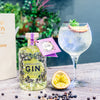 A Boothstown Passionfruit Gin and tonic in a glass next to a bottle of Boothstown Passionfruit gin